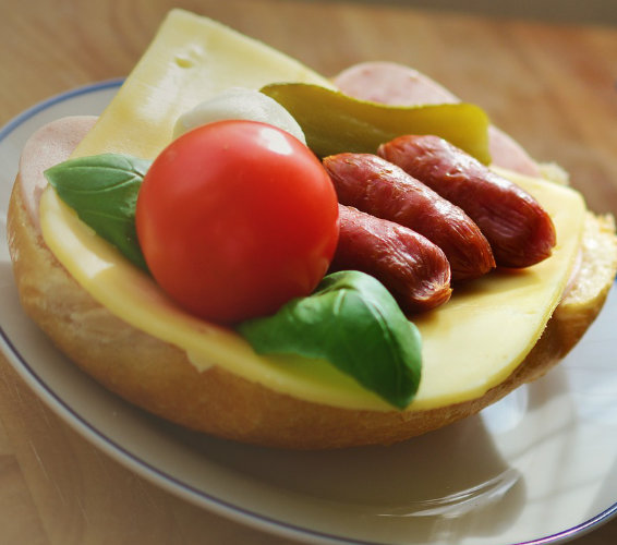 halbes Brötchen mit Käse Tomate und saurer Gurke