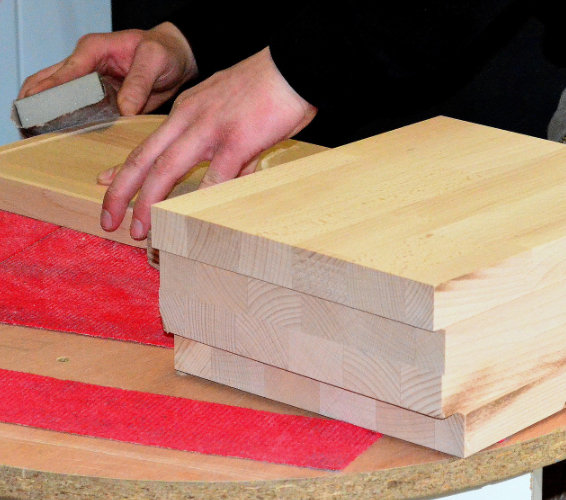 Holz: Holzbretter udn Hand mit Schleifpapier