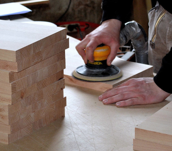 Holzverarbeitung: Holzbretter und Hand mit Schleifgerät