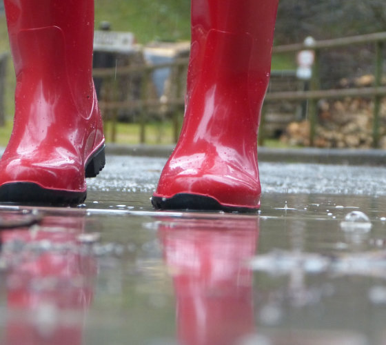 Wetter. Rote Gummistiefel im Regen.