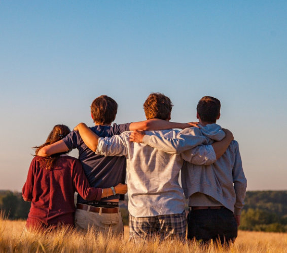 Kursheft. Urlaubsheft. Vier Personen stehen Arm in Arm.