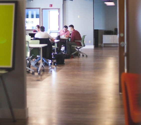 Außenarbeitsplätze. Personen sitzen an einem Tisch zusammen und arbeiten am Computer.