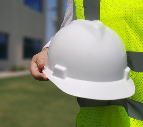 Arbeitssicherheit. Person mit Warnweste und Schutzhelm in der Hand.