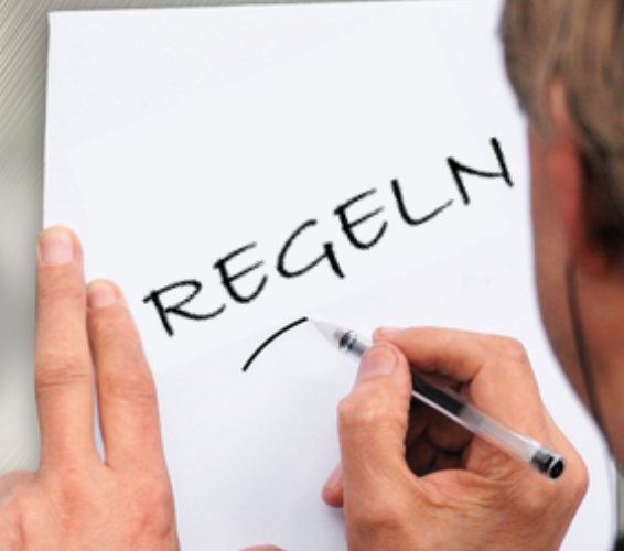Regeln und Pflichten. Person schreibt auf ein Blatt Papier das Wort Regeln.
